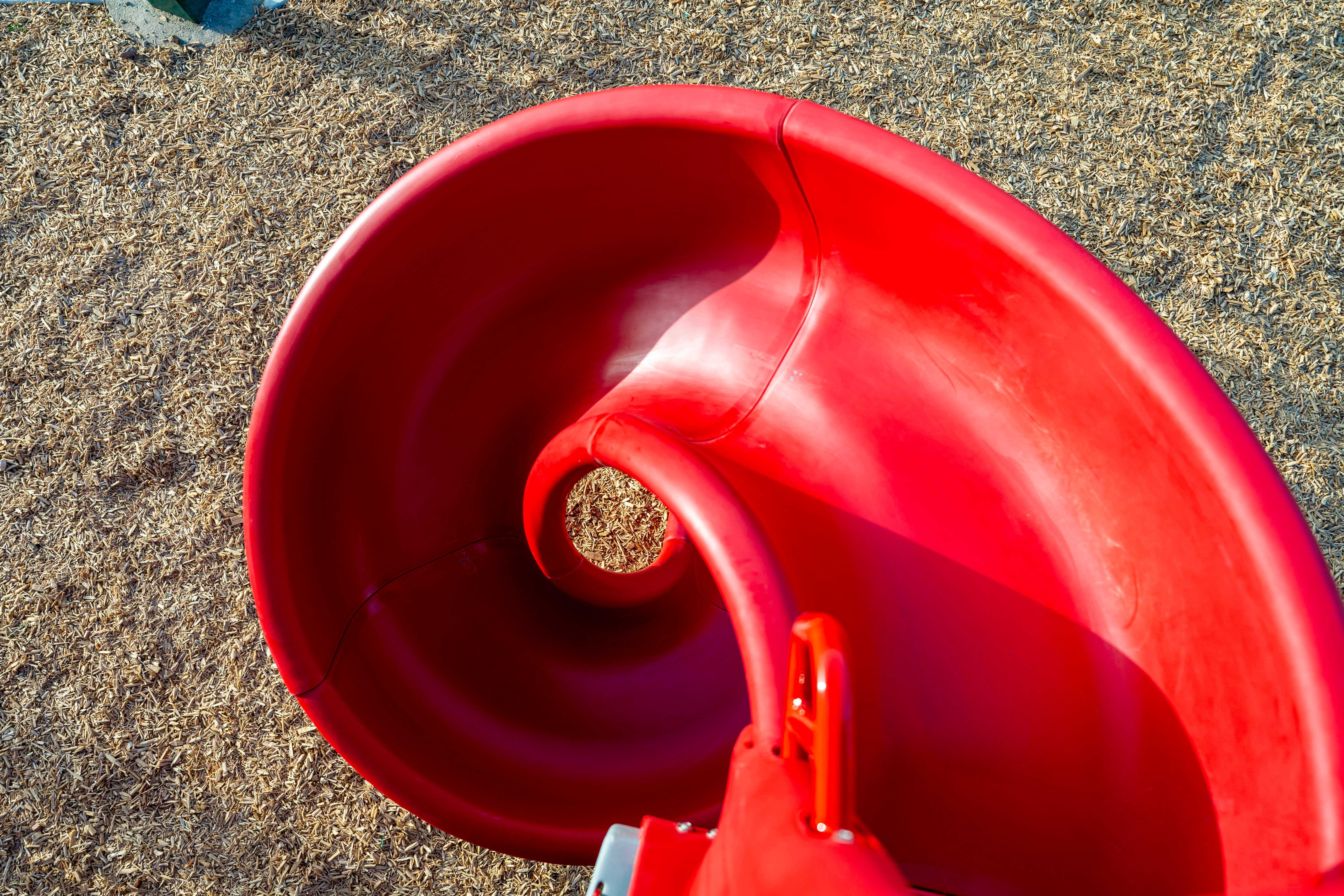 Close-up looking down into a bright red spiral playground slide at Heritage Park.